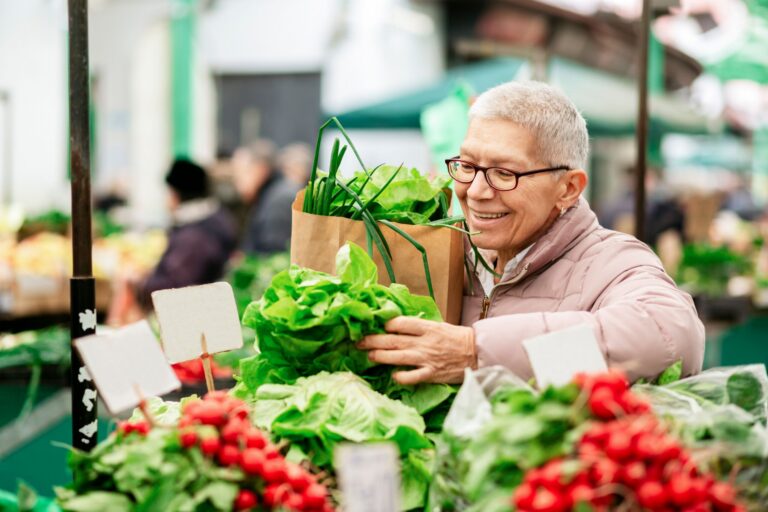 older aged woman selecting produce at a farmer's market