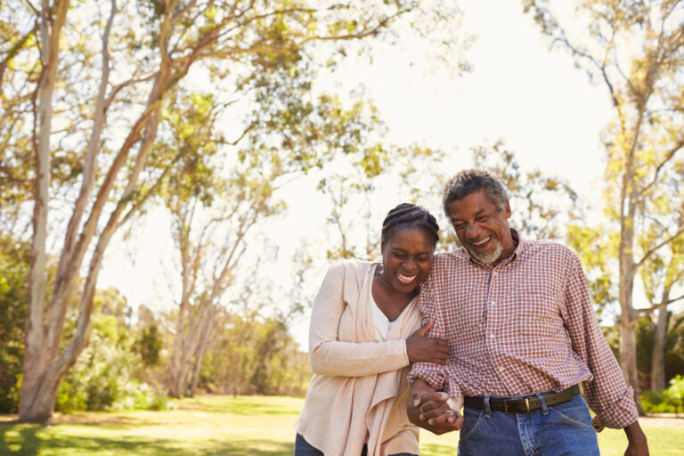 older aged couple laughing while walking outdoors